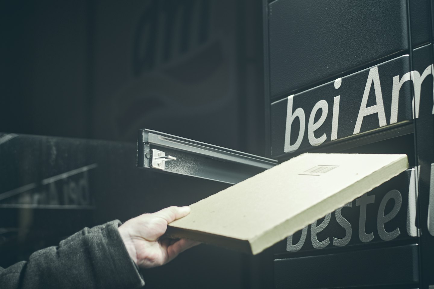 Hand picking up a package from an automated locker system.
