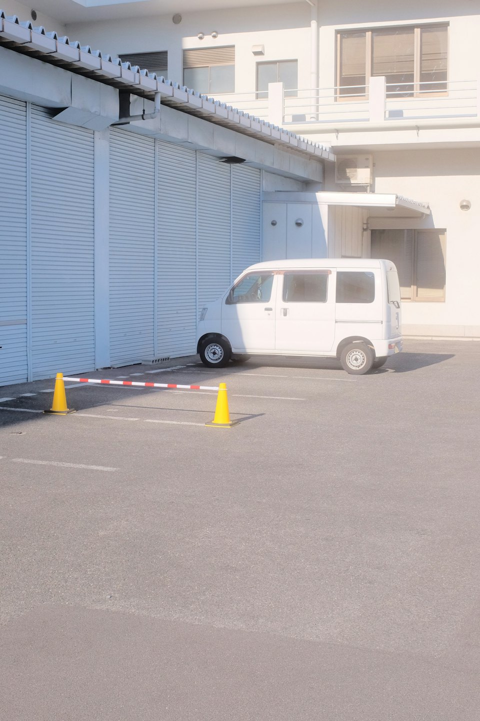 White cargo van parked in front of a modern commercial building.